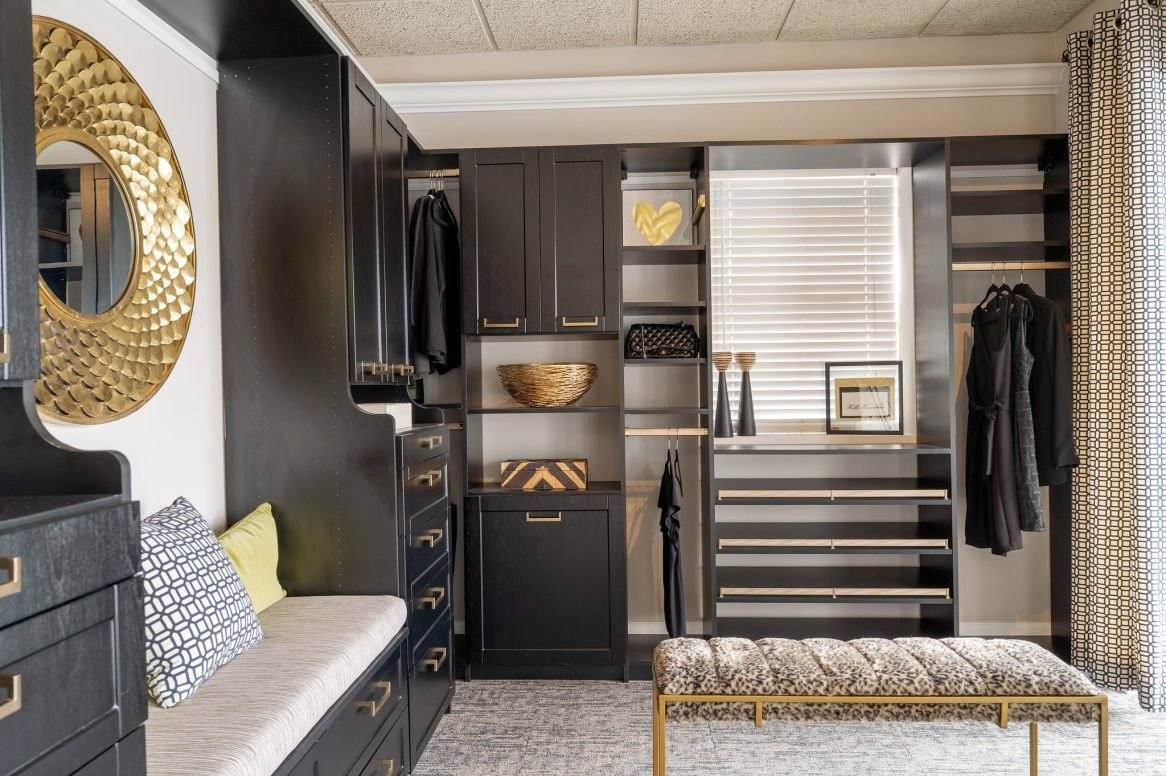 Black closet cabinetry with drawers, a window seat with cushions, pull-out shelves and an upholstered bench