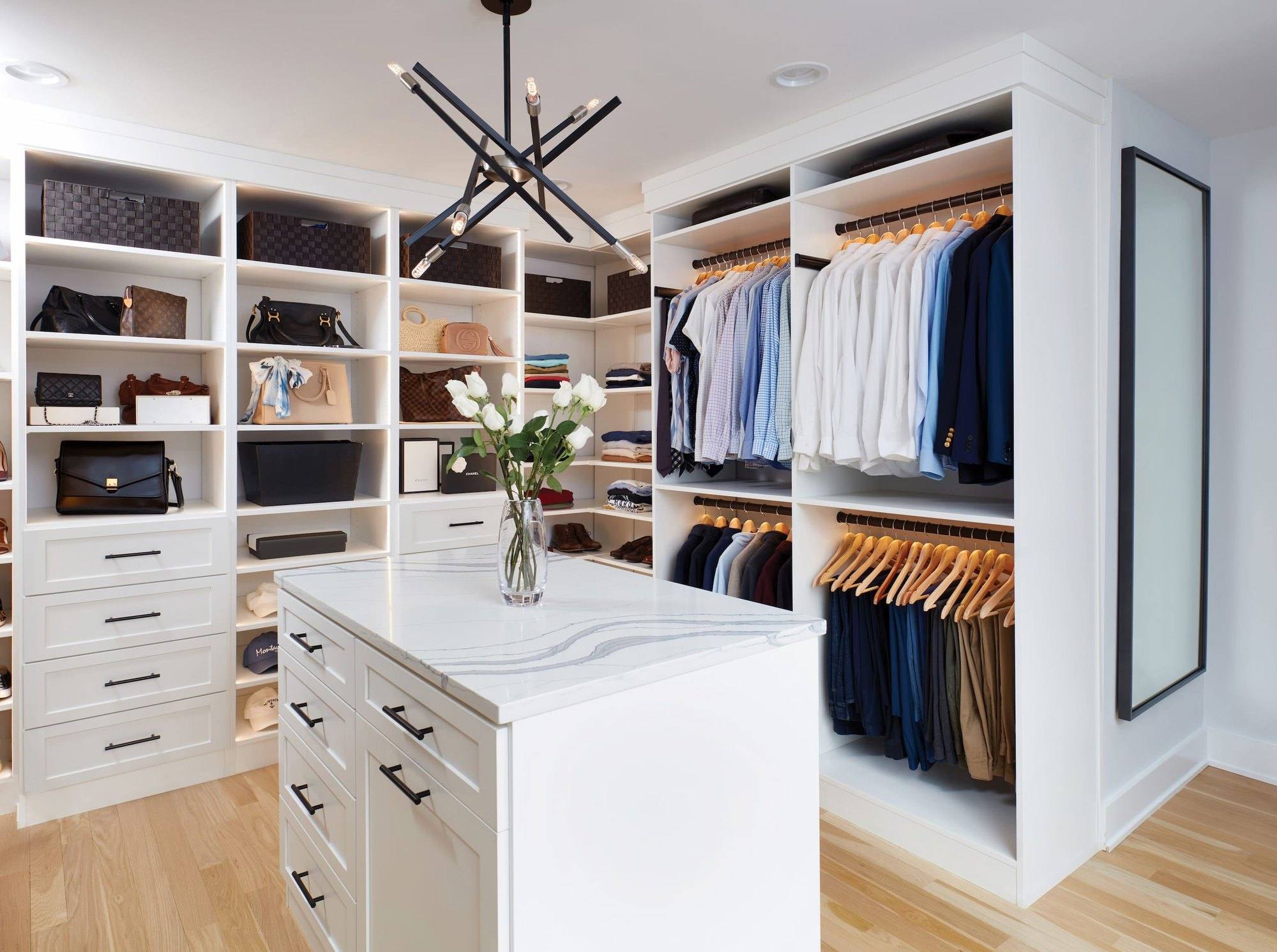 White walk-in closet with a stone-top island, open shelving for handbags, double-hung shirts and a full-length mirror