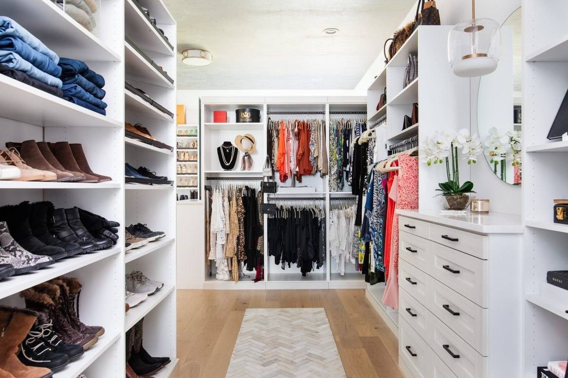 White walk-in closet with open shoe shelves on the left, hanging sections at the back and a run of drawers on the right