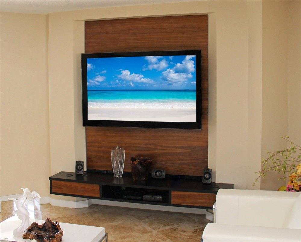 Floating media console below a wall-mounted television set into a wood-tone wall panel