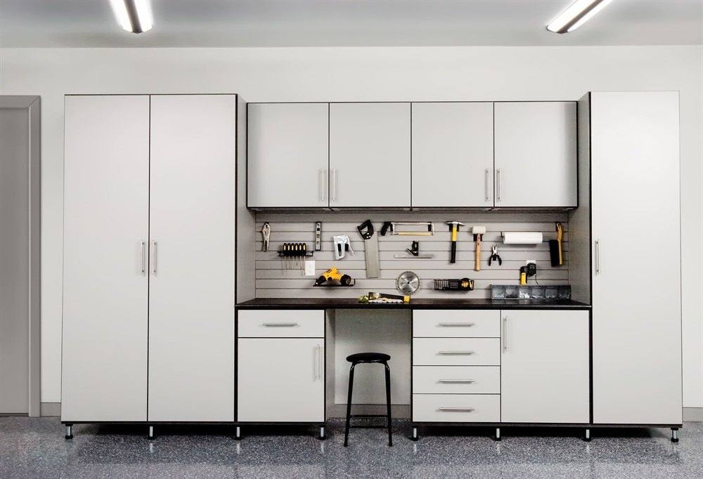 Gray garage cabinets with tall storage, a workbench, wall panel for tools and a stool