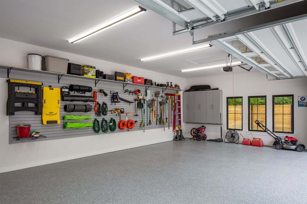 Garage with a wall storage system holding bikes, tools and sports gear above a clear floor, with overhead racks