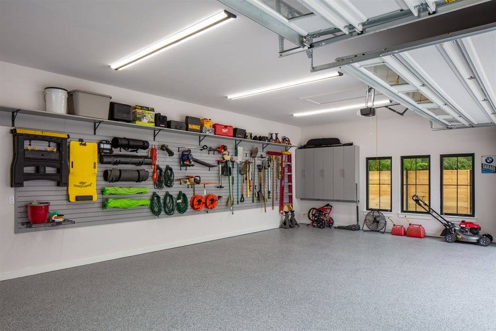 Garage with a wall storage system holding bikes, tools and sports gear above a clear floor, with overhead racks