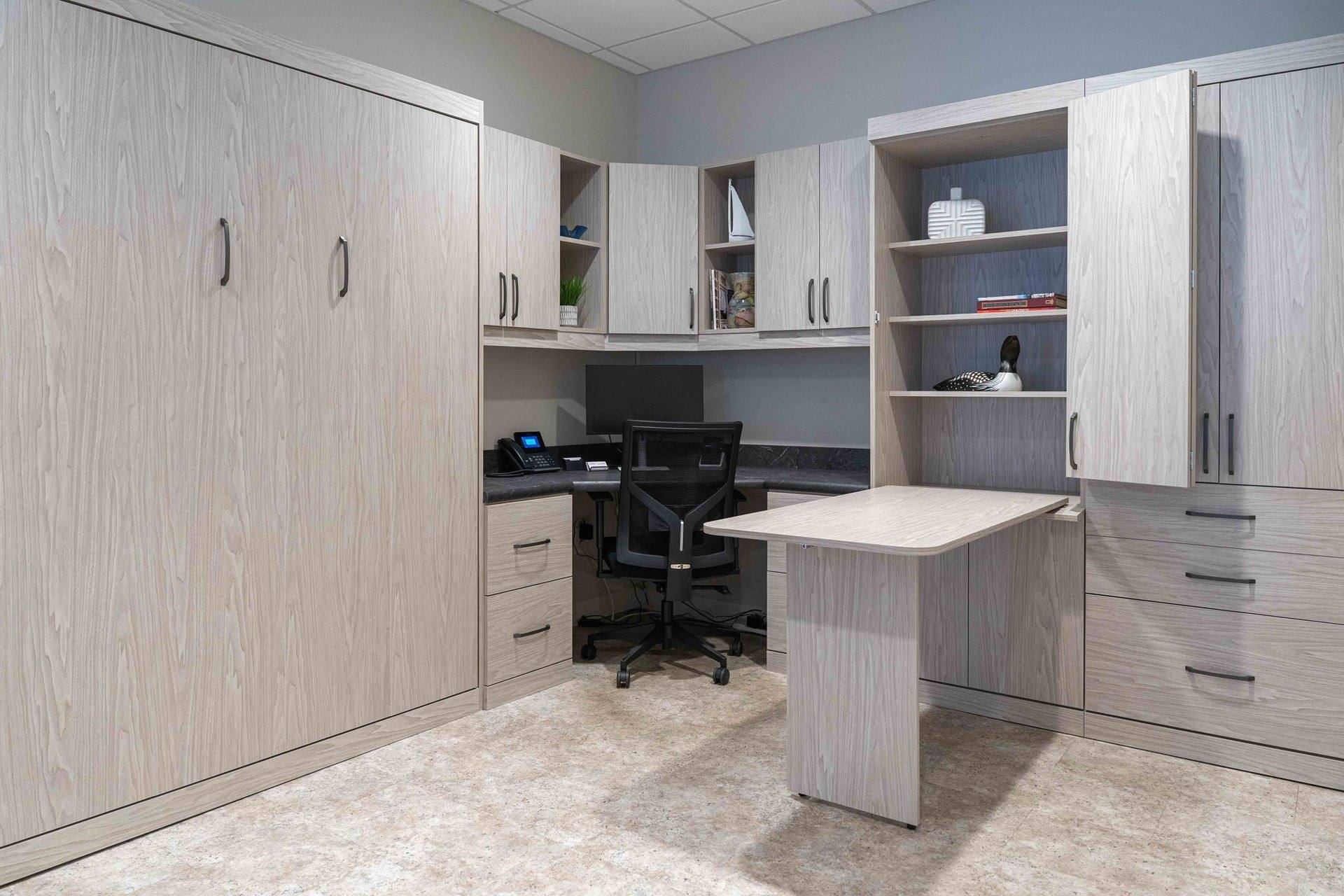 Showroom display pairing a closed Murphy bed cabinet with a corner desk, upper cabinets, shelving and a fold-out work surface